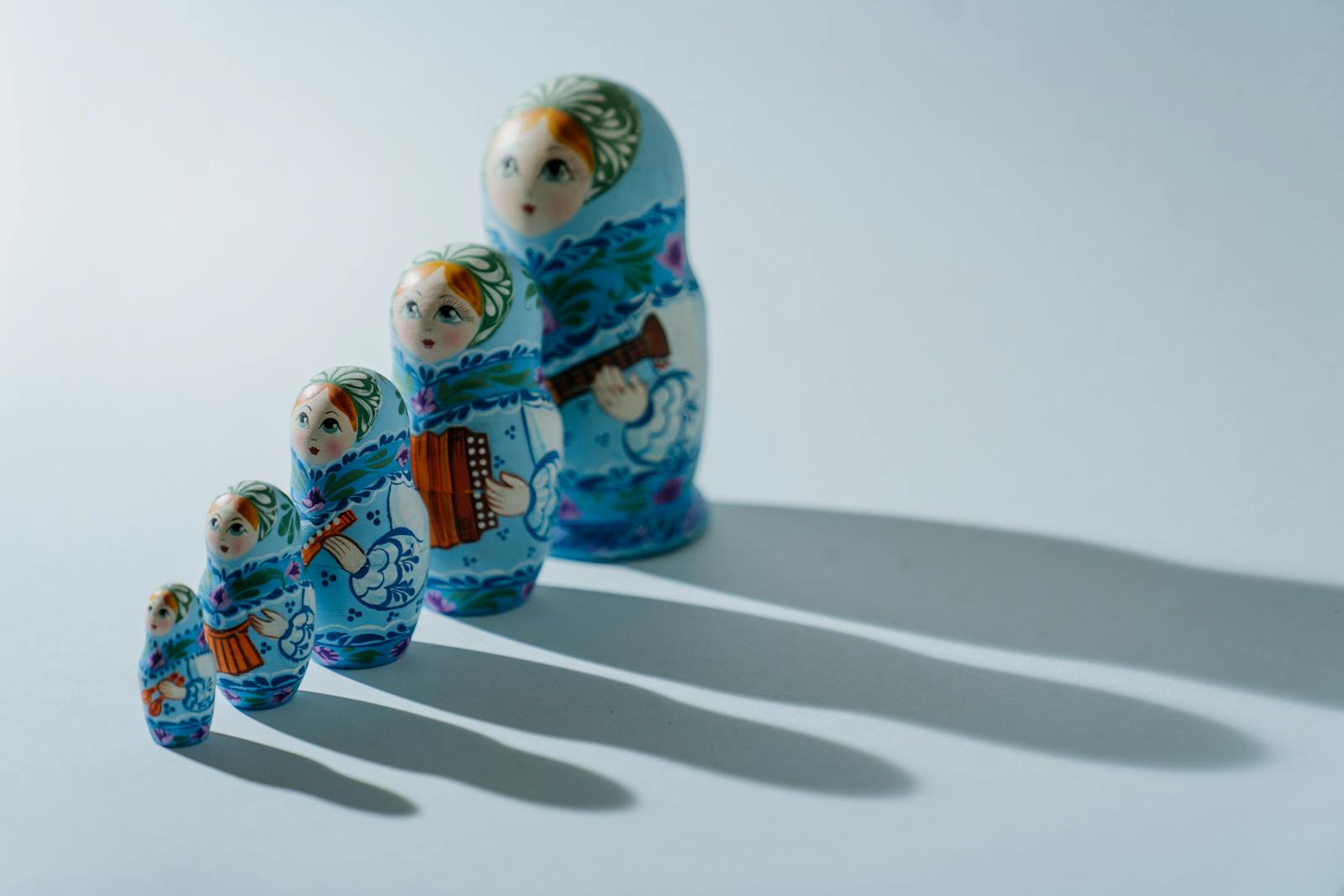 A set of traditional blue matryoshka dolls casting shadows in bright light.